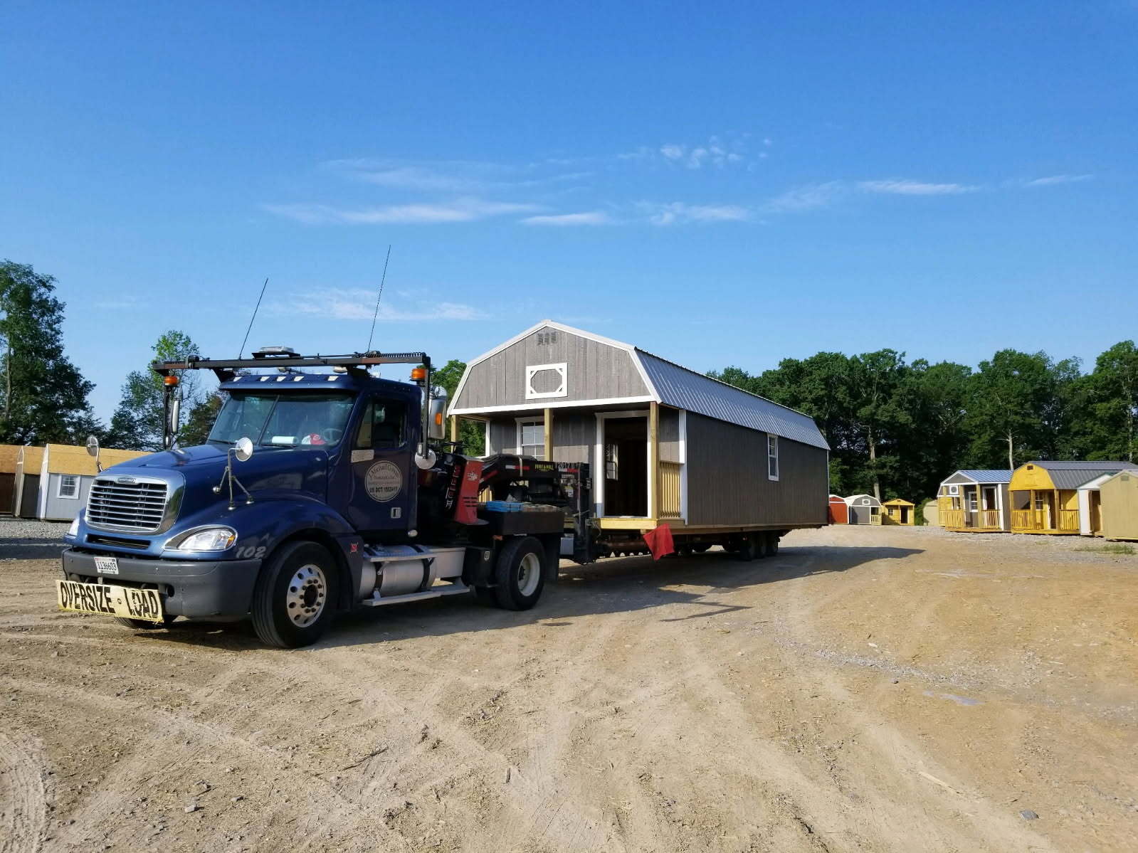 The Shed Superstore delivery truck carrying a storage building